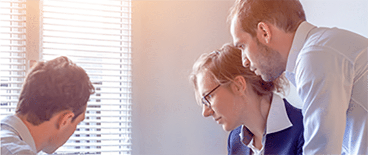 A group of people reviewing information on a laptop.