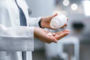 Doctor taking pain and stress relief medicine to help with mental health during cover fatigue. Medical healthcare professional nurse showing the correct drug dose by pouring the pills in her hands