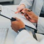 closeup of healthcare employees looking over chart on clipboard