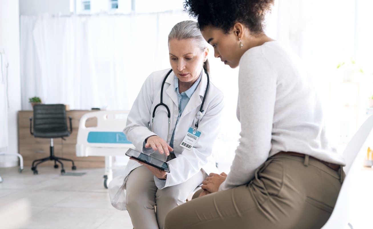 doctor talking to patient showing her something on a tablet
