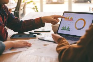 two people looking at laptop with graphs on montior