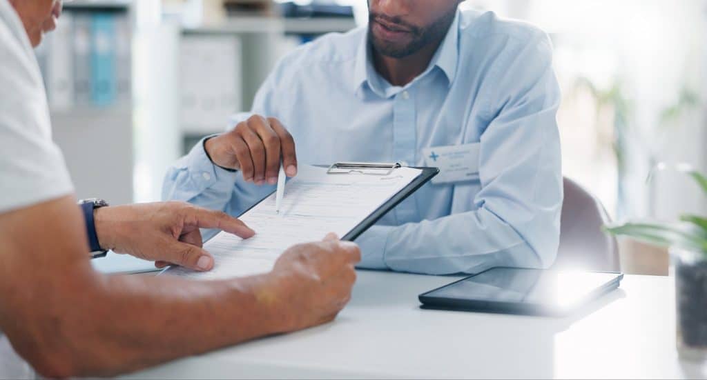 Man, hands and doctor consulting patient with clipboard, documents or insurance for healthcare